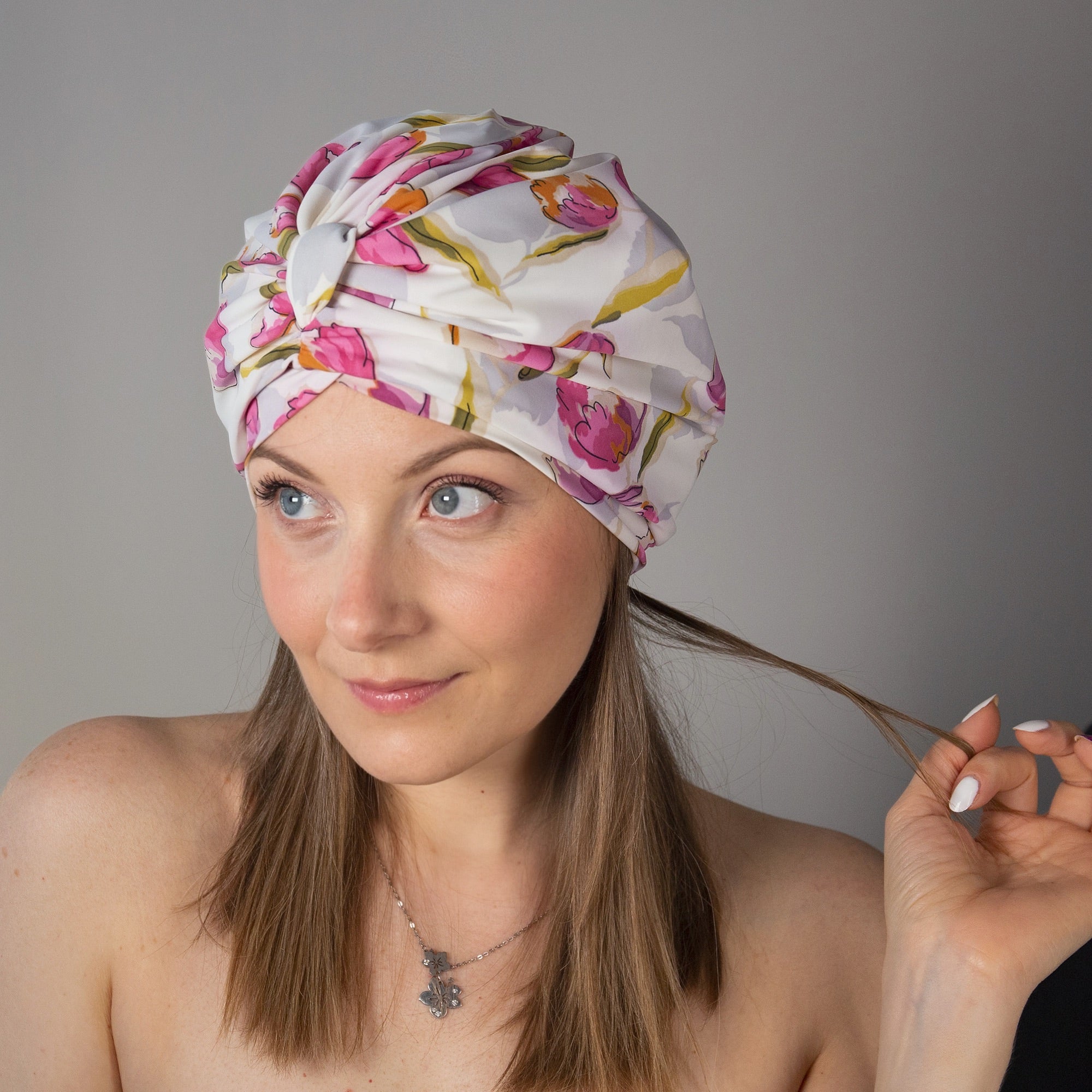Woman wearing a tulip print drying turban against a grey background