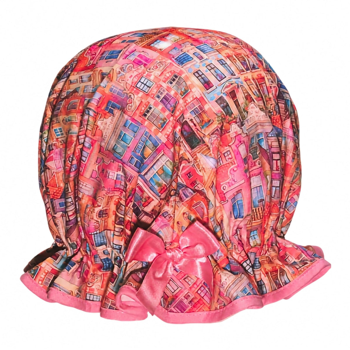Vintage style women's roomy cotton shower cap. Frilled edge, colourful townhouse print in warm sun set feel tones of pink, orange and purple. Trimmed in a warm pink with matching satin bow.