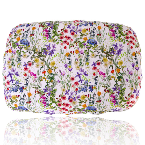 Soft waterproof rectangular bath pillow covered in a multicoloured meadow floral cotton print on a white background. Two suckers on reverse.

