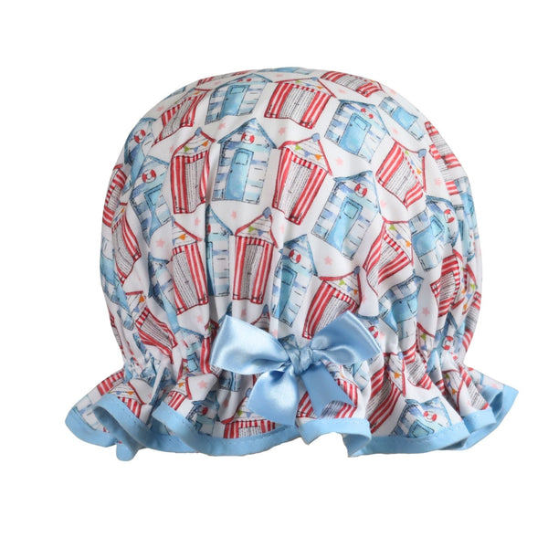"Vintage style women's roomy cotton shower cap featuring multi-coloured beach huts on a white background. Trimmed sea blue with matching satin bow.
"
