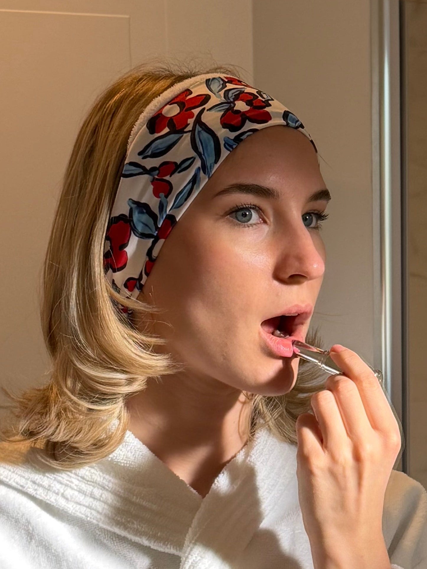 woman putting on makeup wearing a red and blue flower print hairband