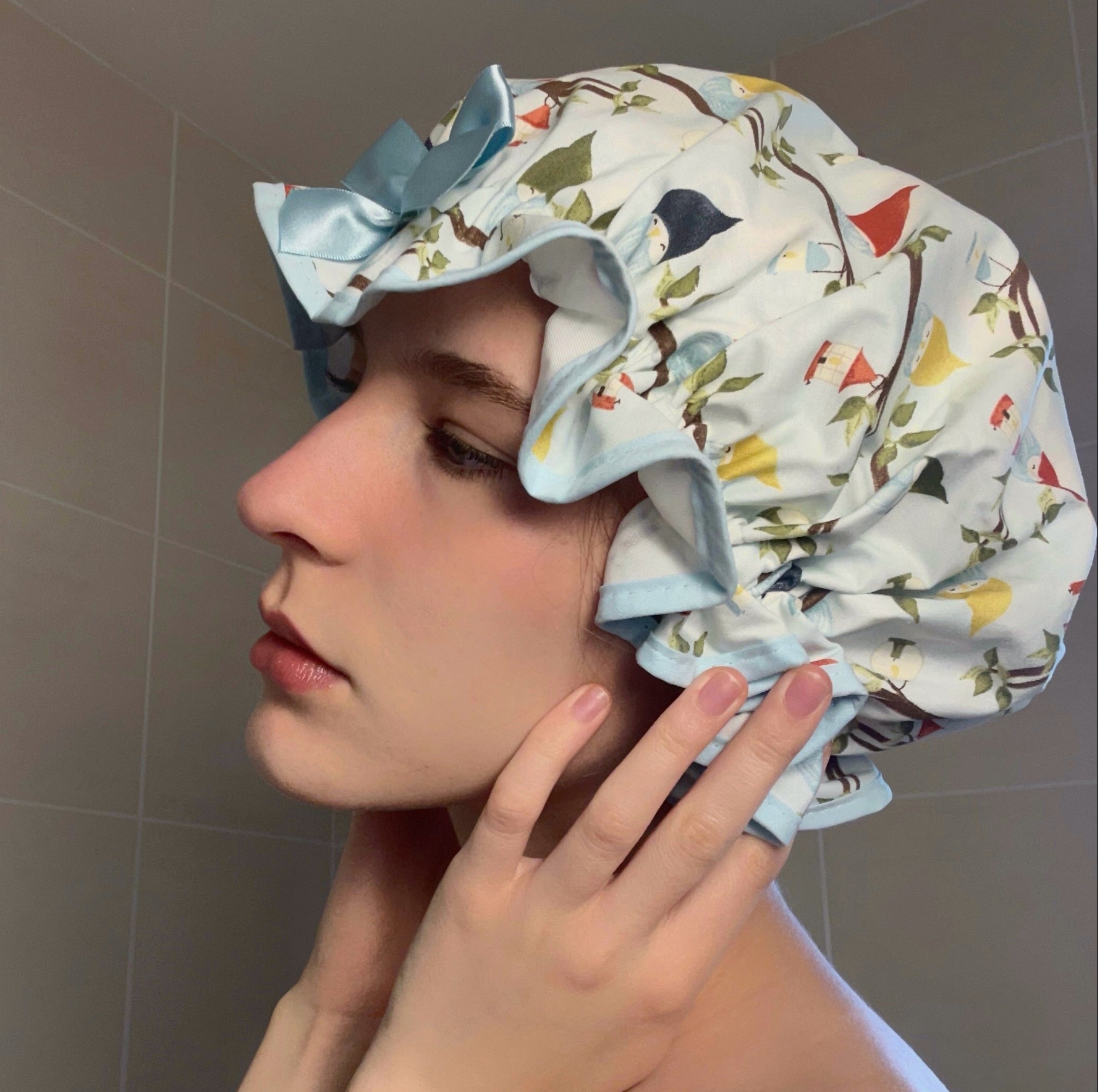 Woman wearing a colourful blue shower cap with an owl print in a bathroom setting