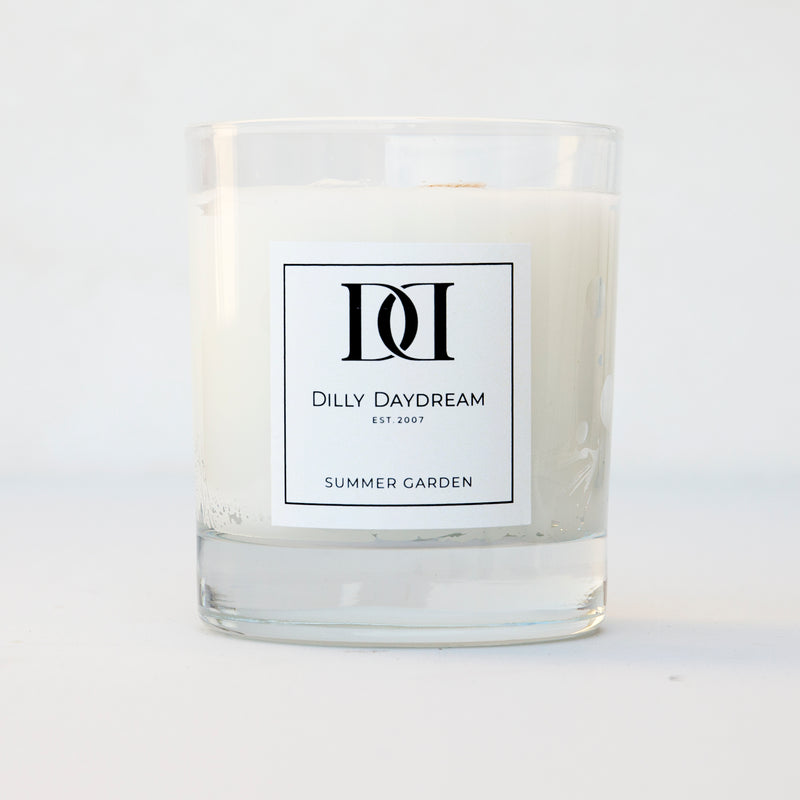 White wax candle with wick in clear glass tumbler