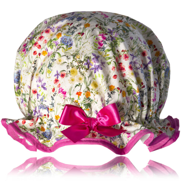 Vintage style, women’s large cotton shower cap. Frilled edge, multicoloured meadow floral print on a white background.  Trimmed in cerise with matching satin bow.
