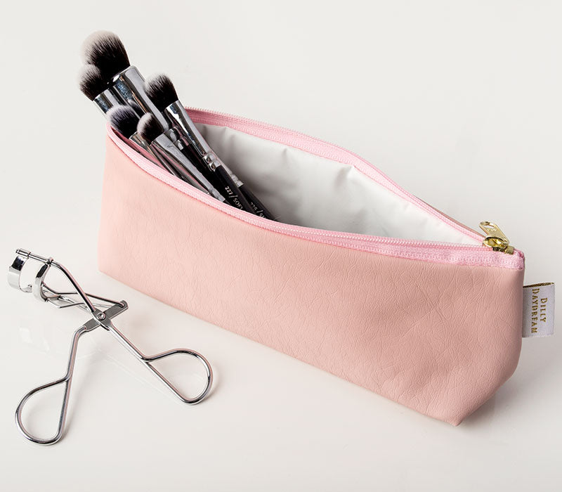 Small triangular zip top make up bag.  Pale pink soft leatherette with pink zip.  Waterproof lining.