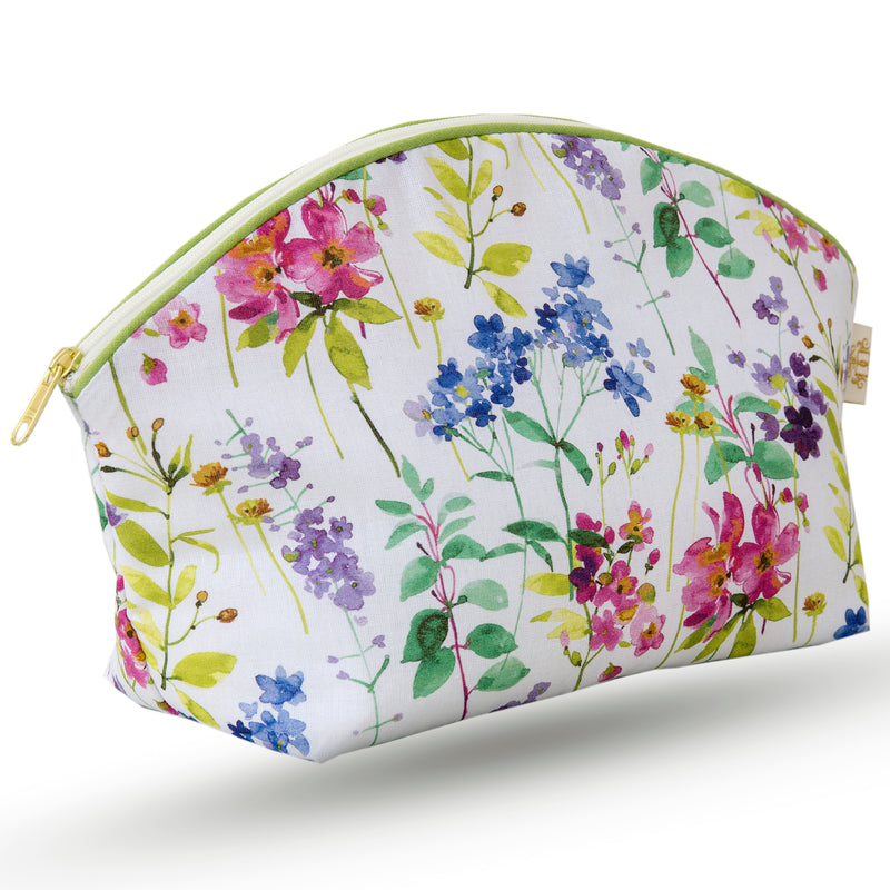 Curved zip top cotton sponge bag. Multicoloured meadow print in blue, pink and purple on a white background.  Trimmed in pale green with matching zip.