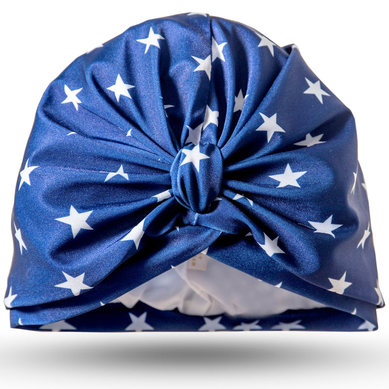 White stars on navy blue lycra pull on waterproof turban, with pretty and gather and knot at front.