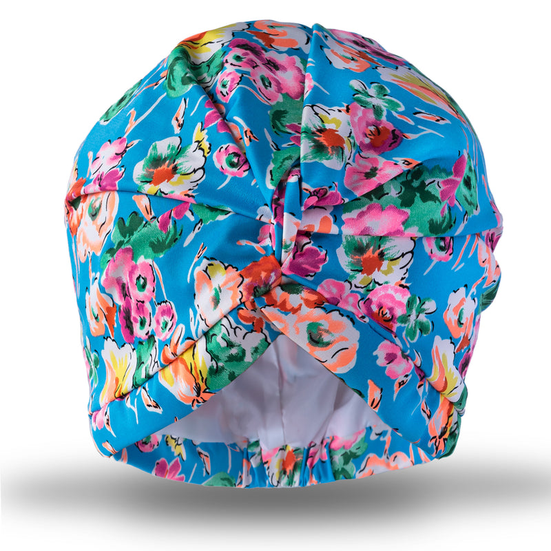 Bright blue background and multi coloured floral print pull on waterproof turban, with pretty gathered knot at front.